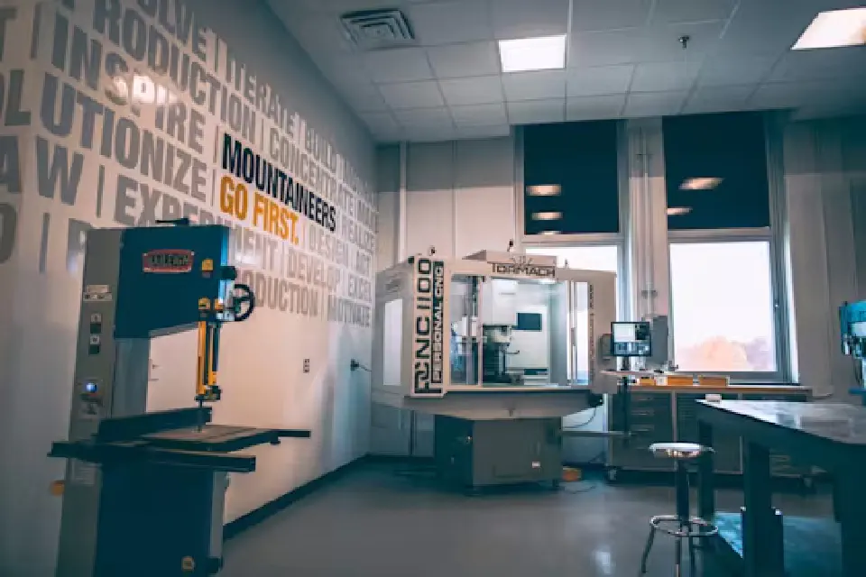 A Baileigh band saw and Tormach milling machine in a modern work space that includes the "Mountaineers Go First" tagline on one of the walls.